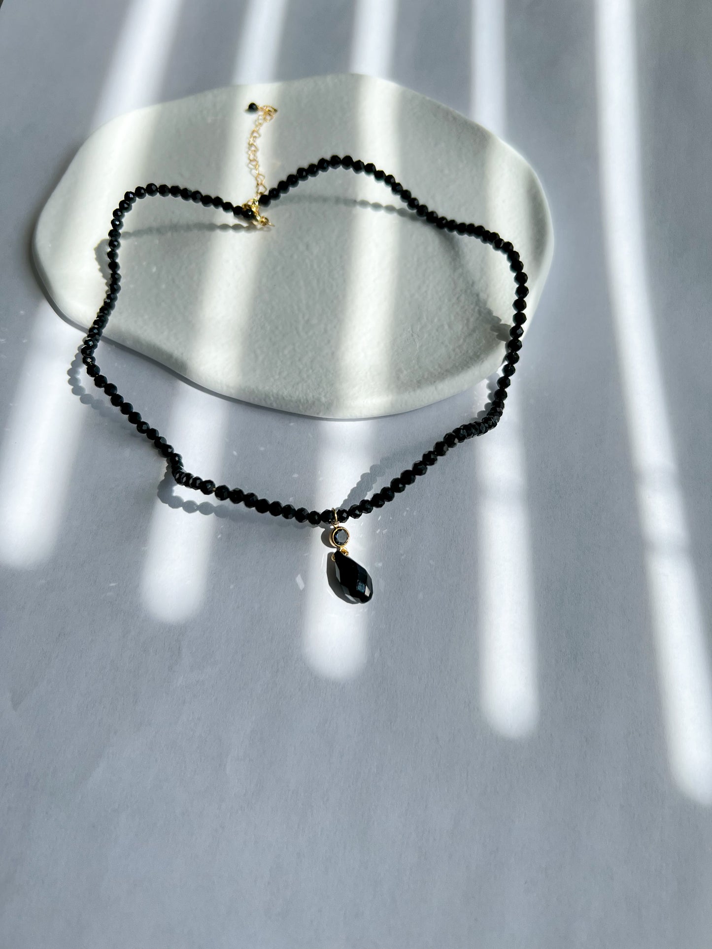 Black wave curve choker necklace on a white plate