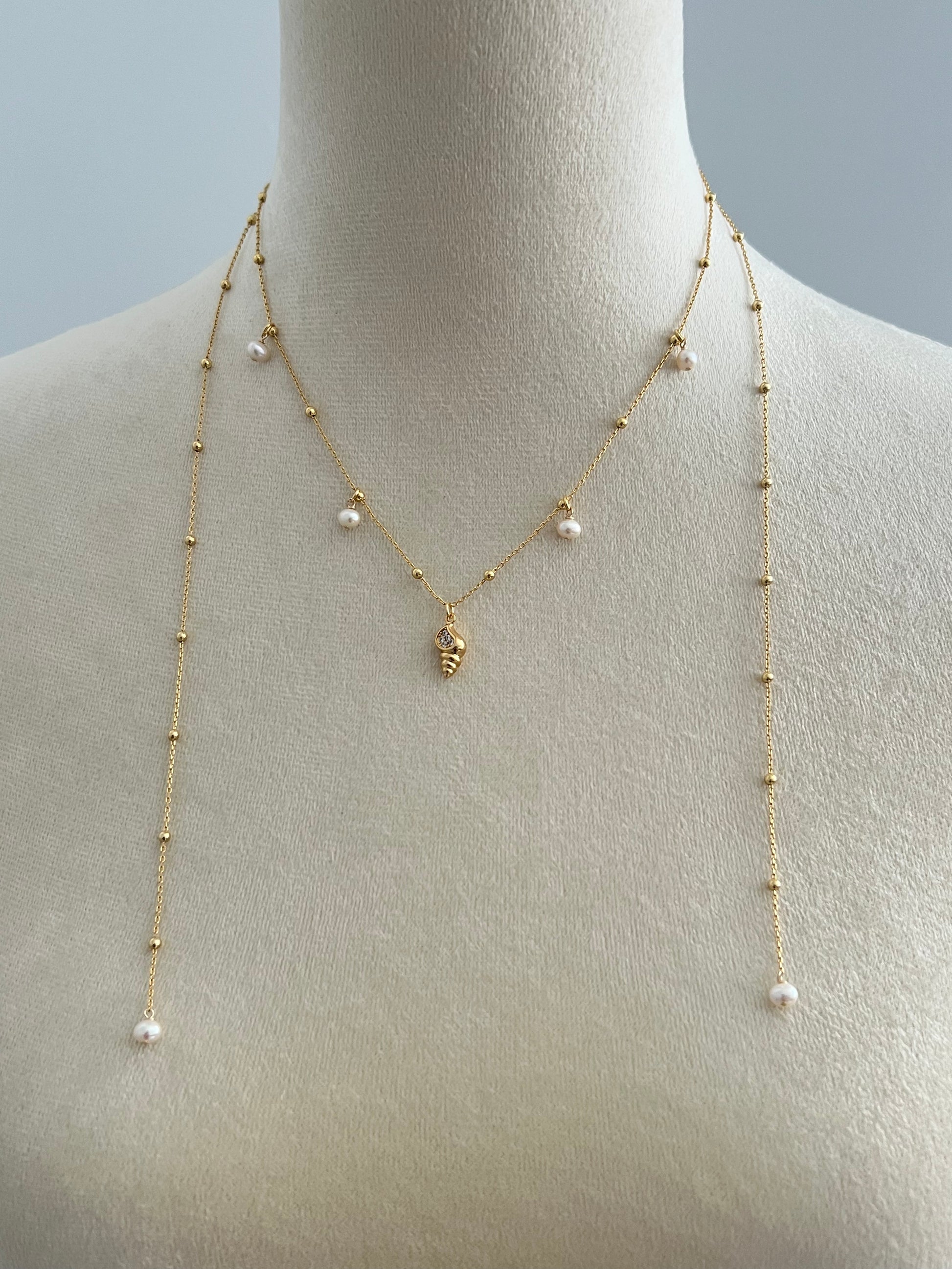 pearls & golden conch layered necklace on a mannequin