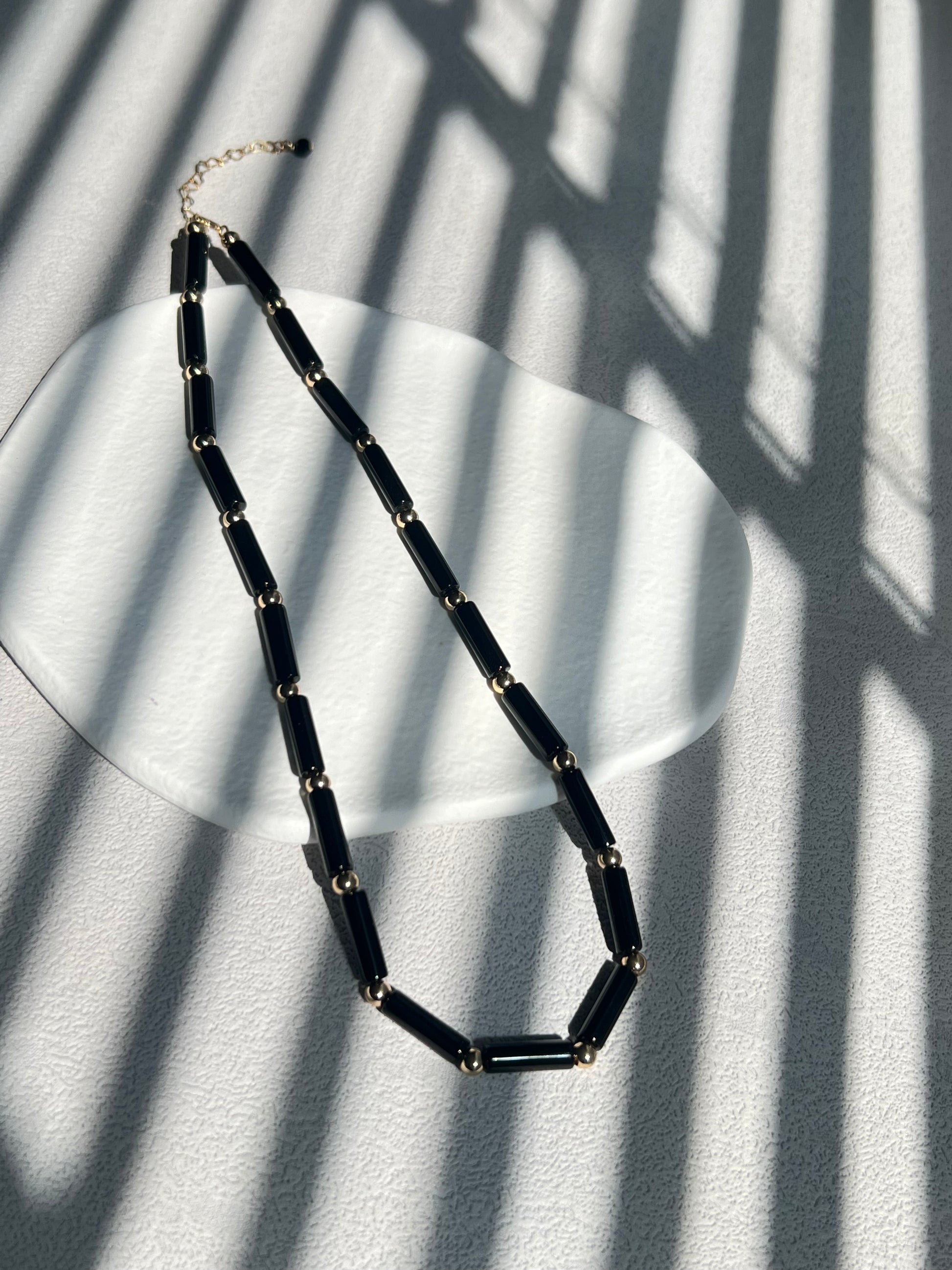 Black agate choker necklace on a white plate