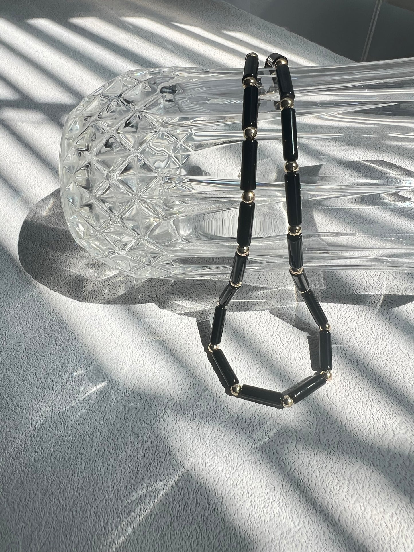 Black agate choker necklace over a crystal clear glass