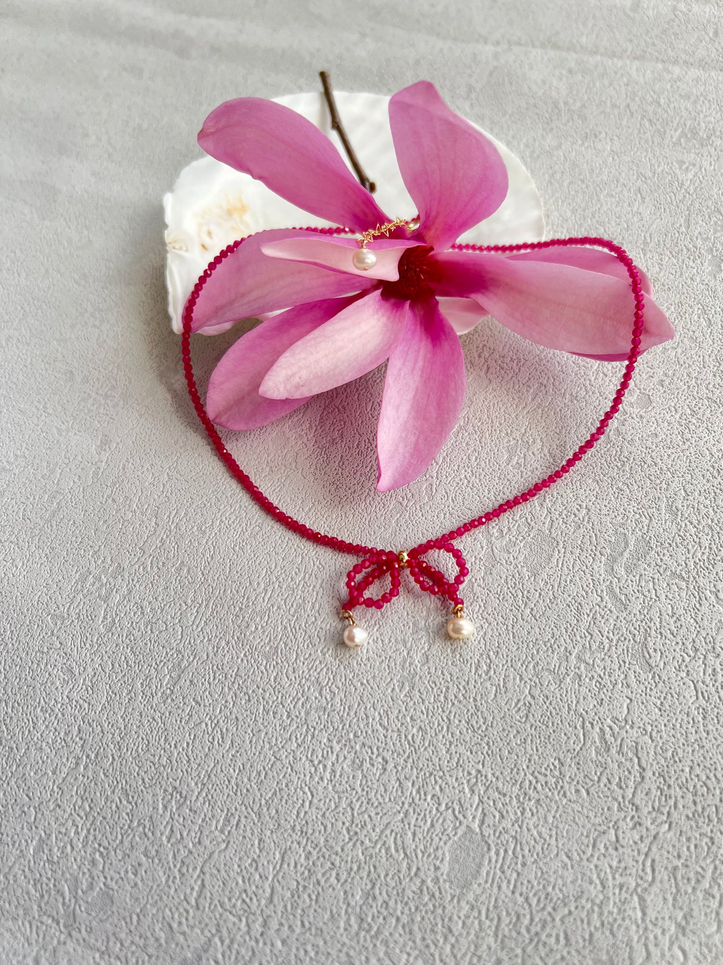 Pink gemstones choker necklace with a knot over a pink flower