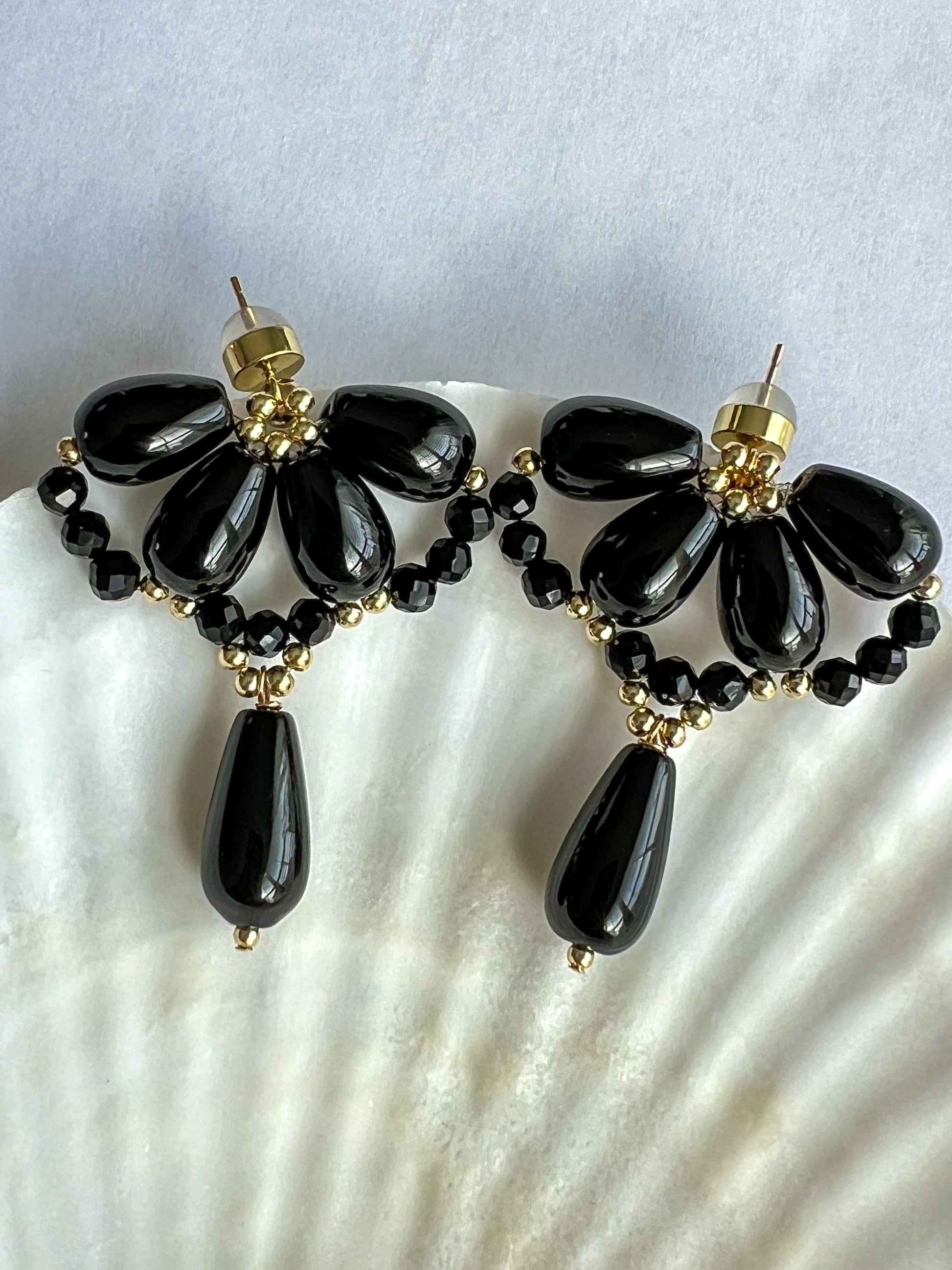 Black agate waterdrop earrings on the edge of a shell