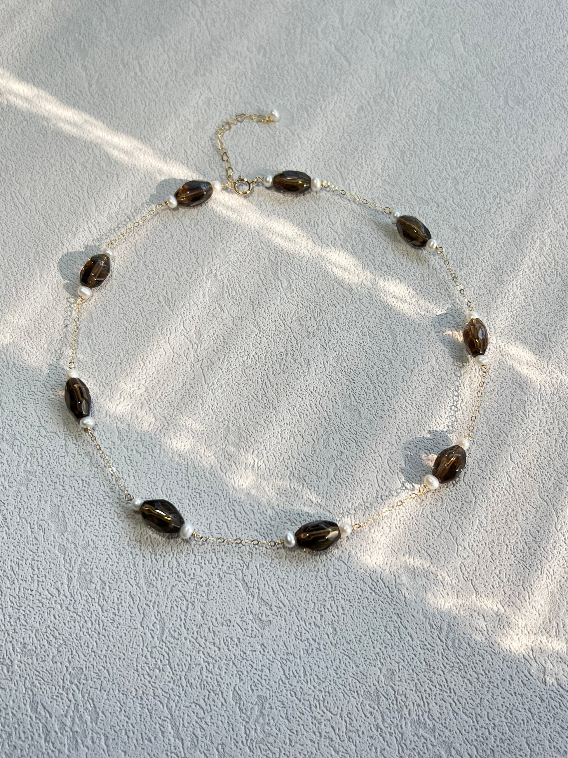 Smoky quartz & pearl choker necklace under light