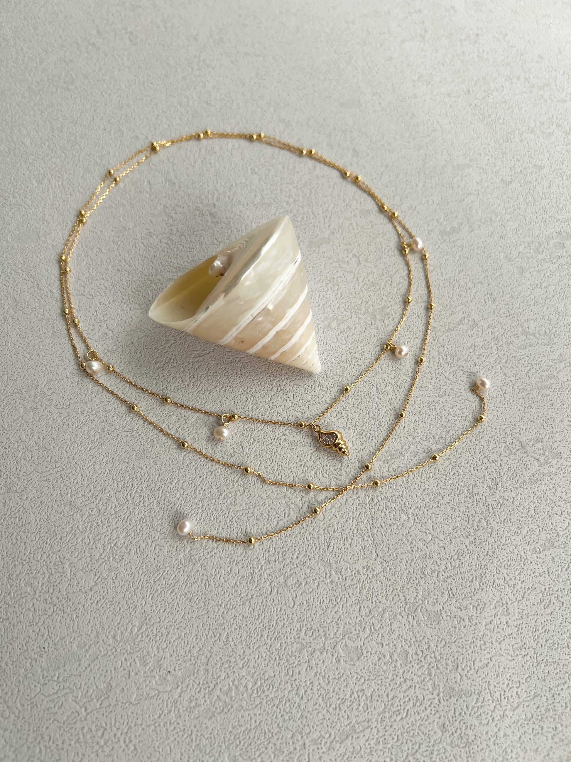 Pearls & golden conch layered necklace around a big conch