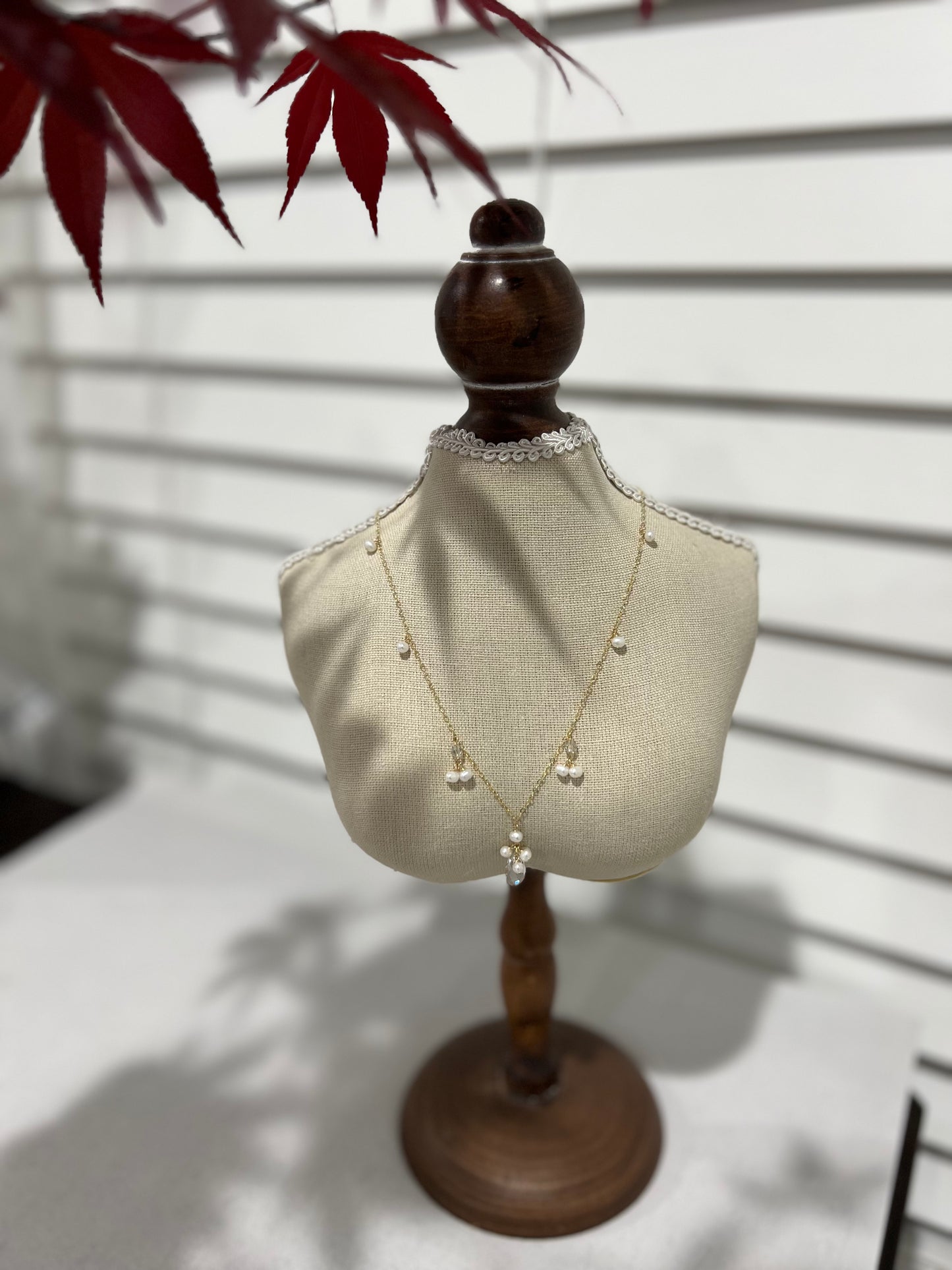 Swarovski crystal & pearls necklace on a mannequin next to maple leaves