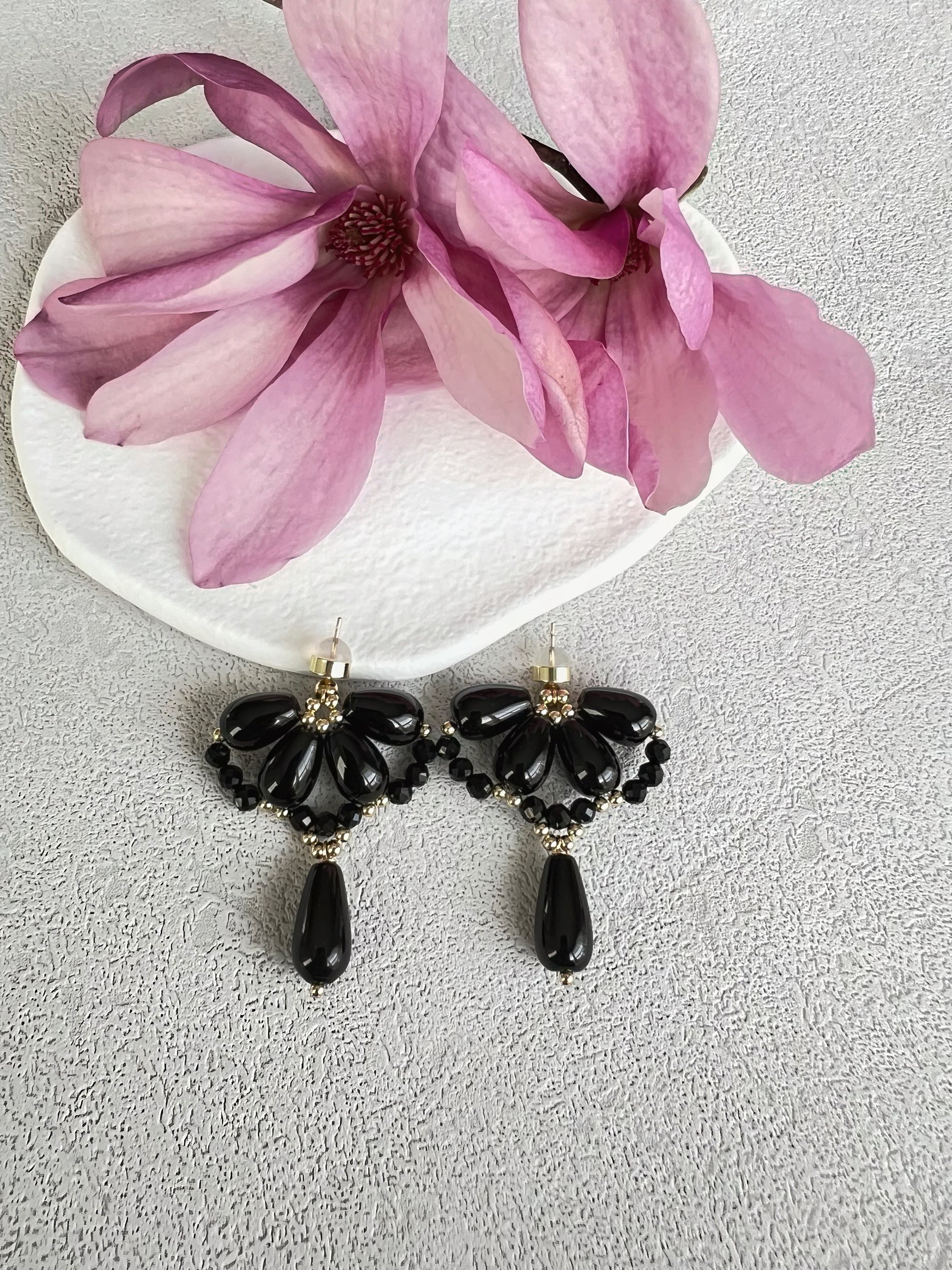 Black agate waterdrop earrings on a white plate with pink flowers