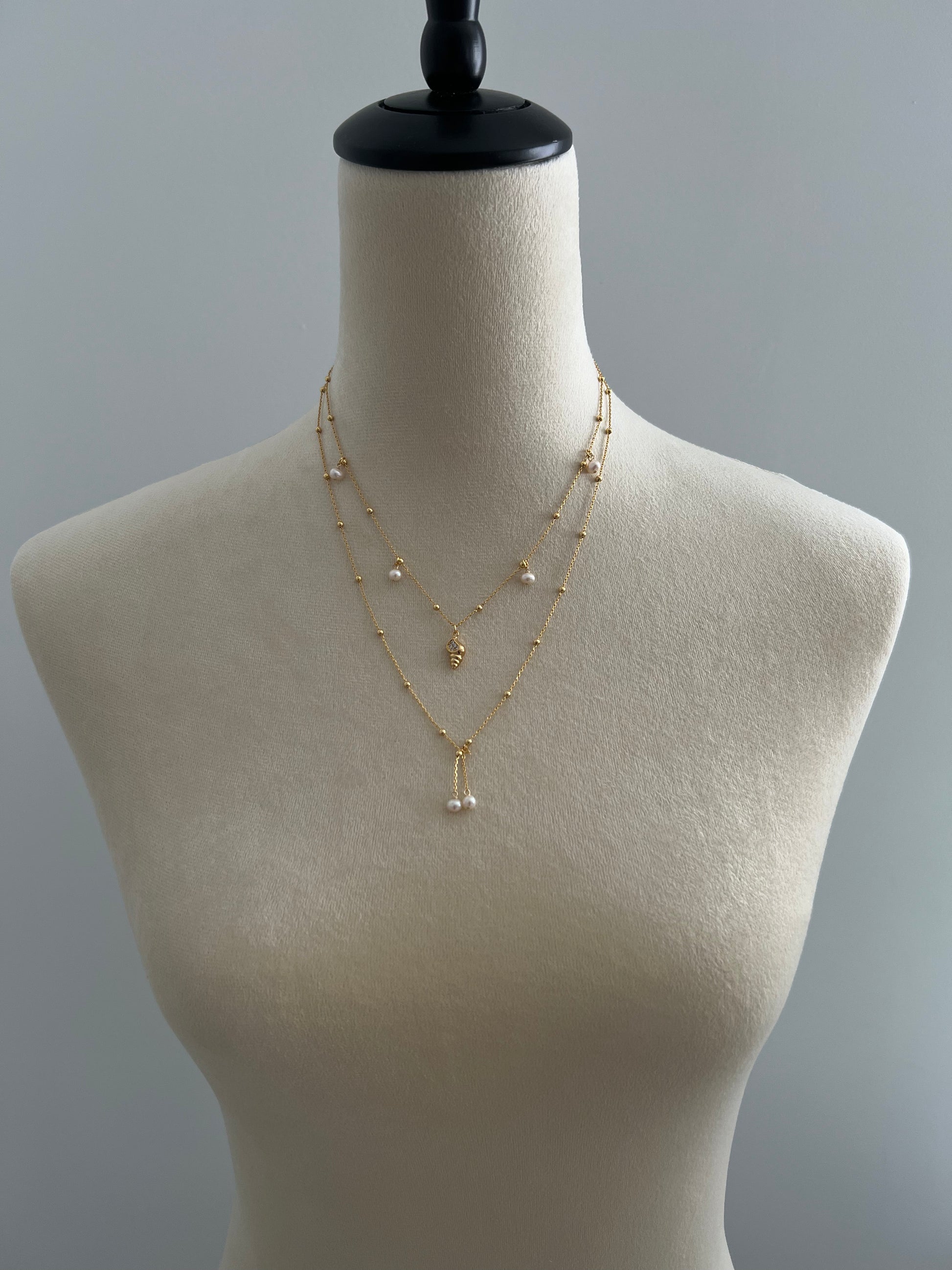 Pearls & golden conch layered necklace on a mannequin