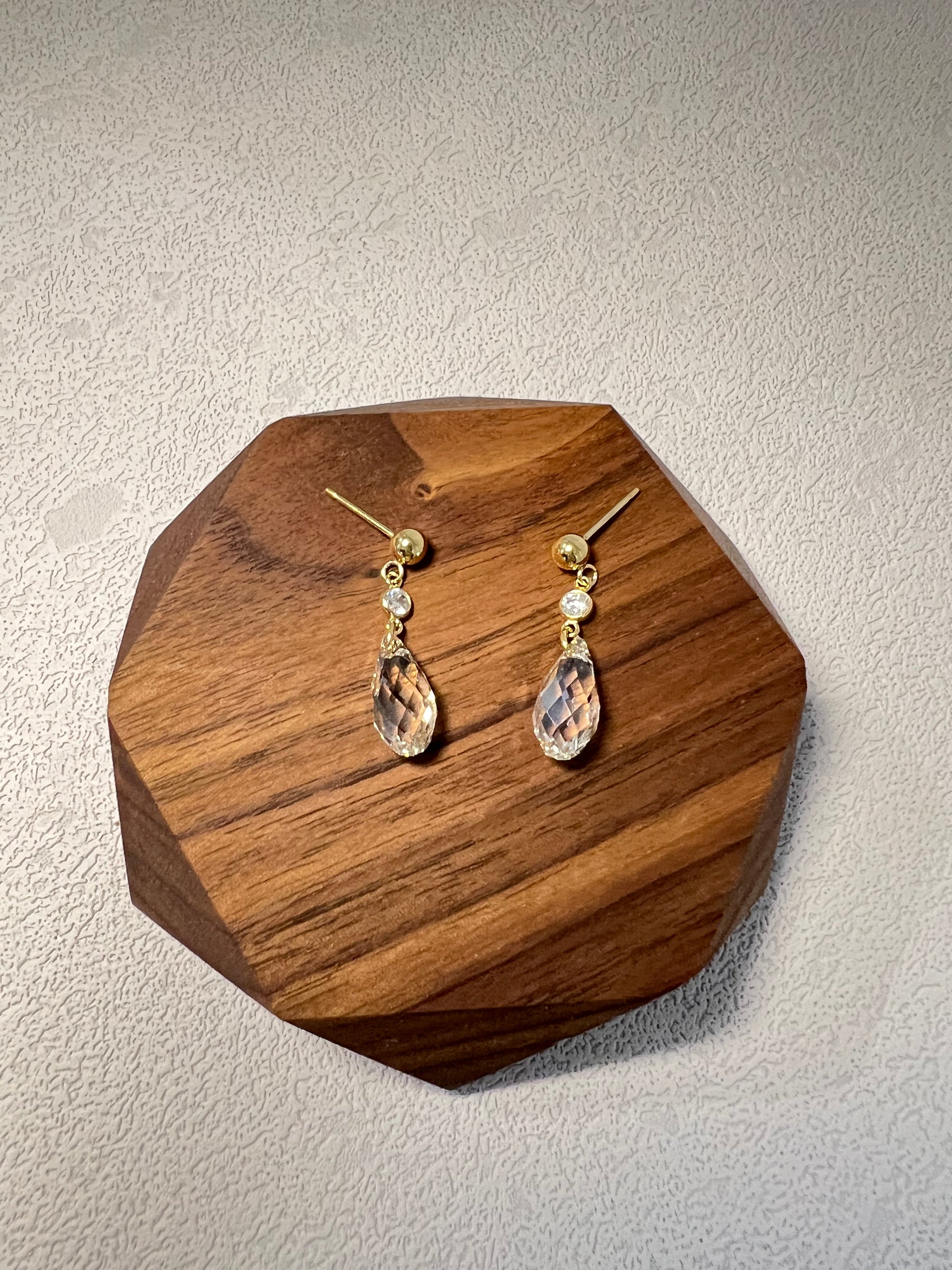 Shiny Swarovski crystal earrings on a wood display plate