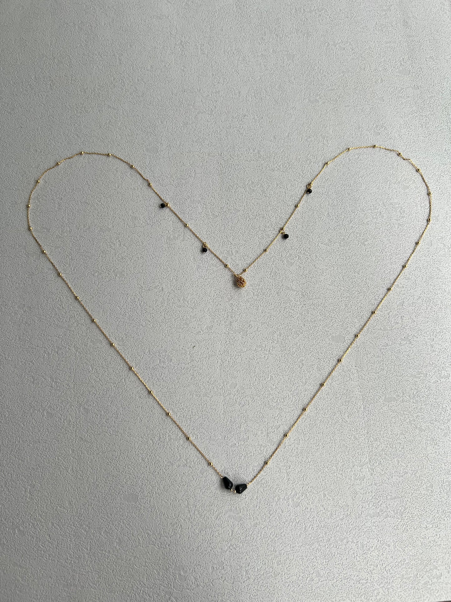 Pinecone layered necklace laid out a heart shape