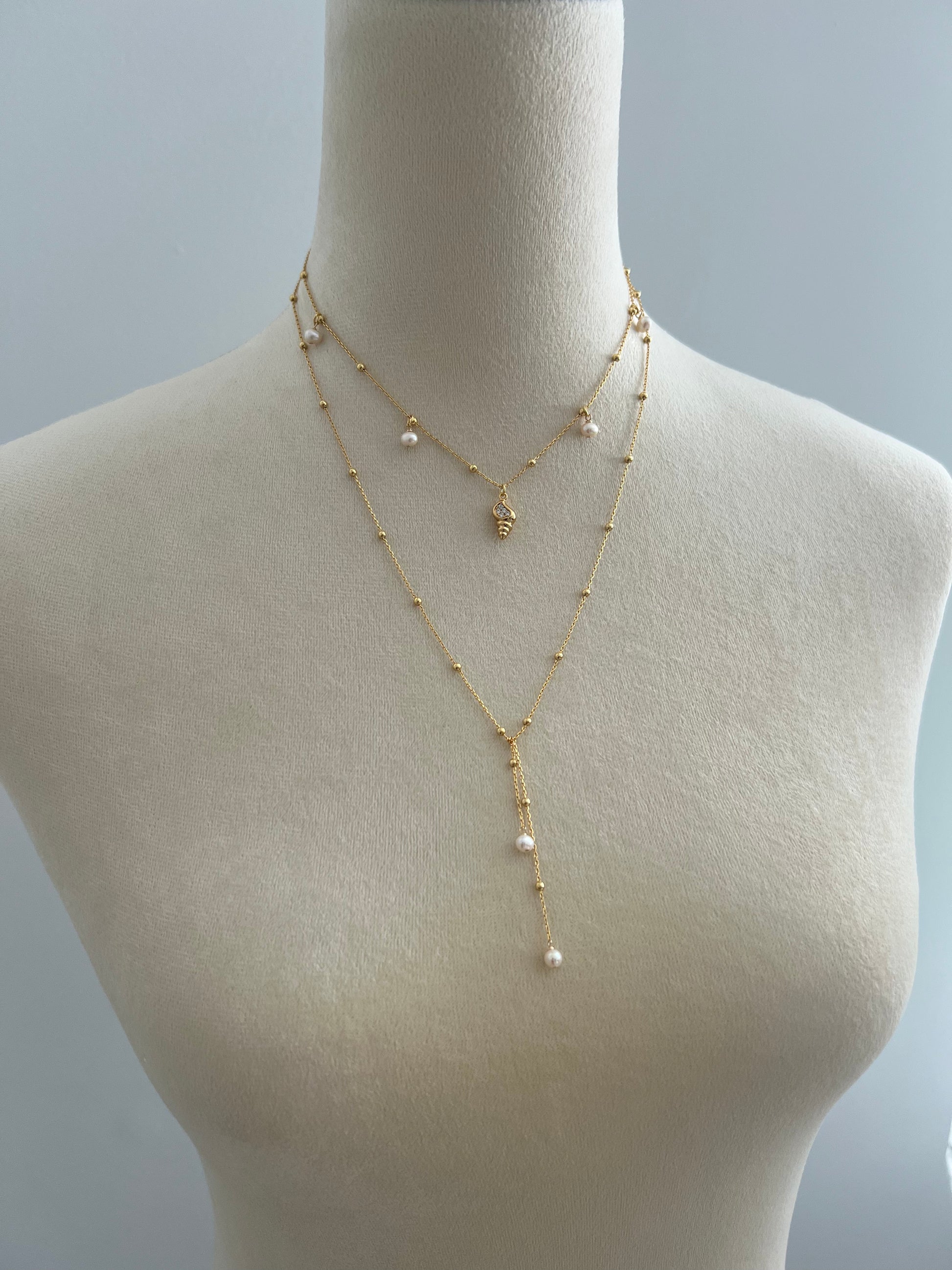 Pearls & golden conch layered necklace on a mannequin