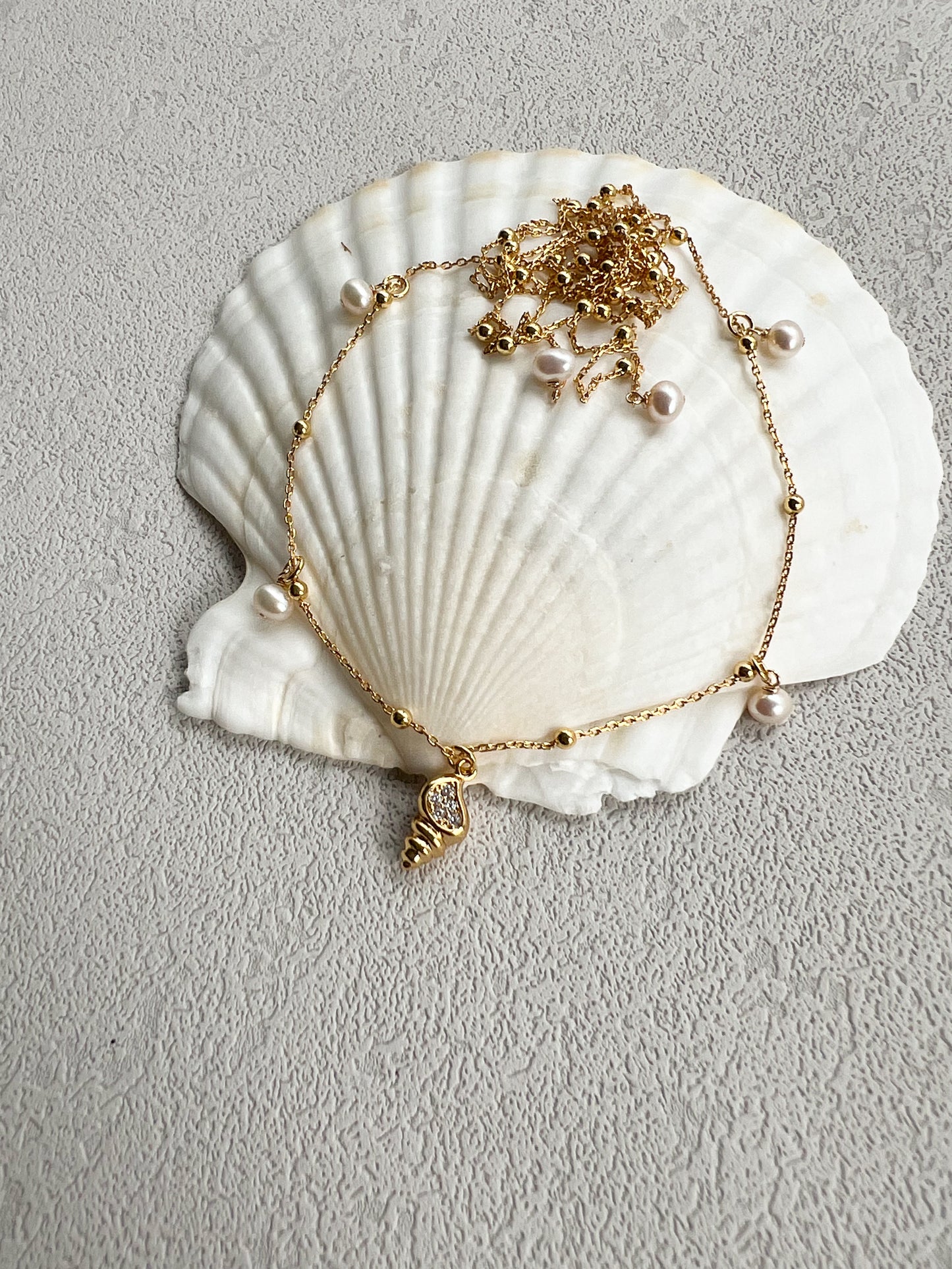 Pearls & golden conch layered necklace on a big shell