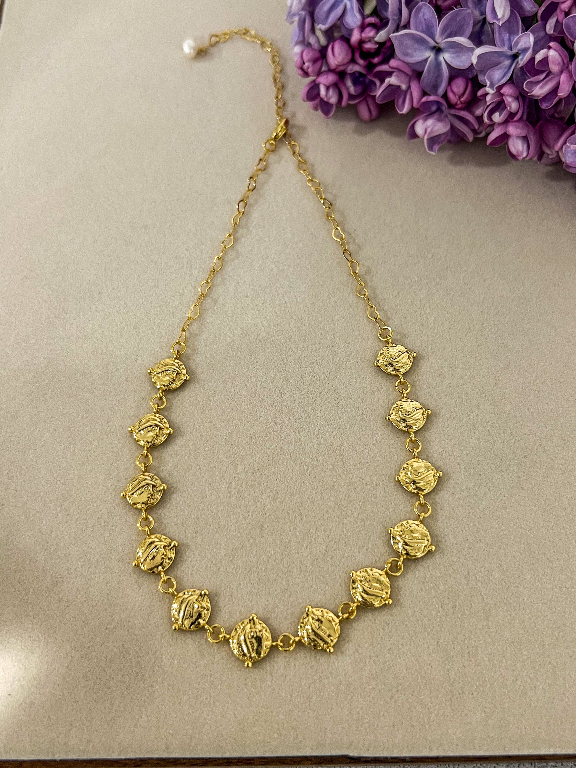 24k gold plated cascading coin choker necklace next to flowers